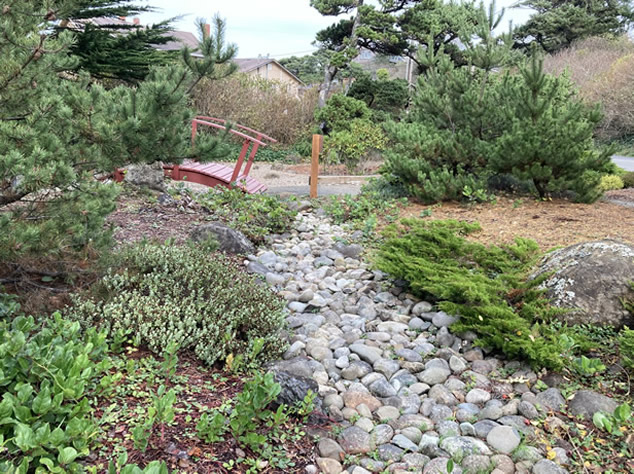 Japanese garden stone river with small red bridge in the background